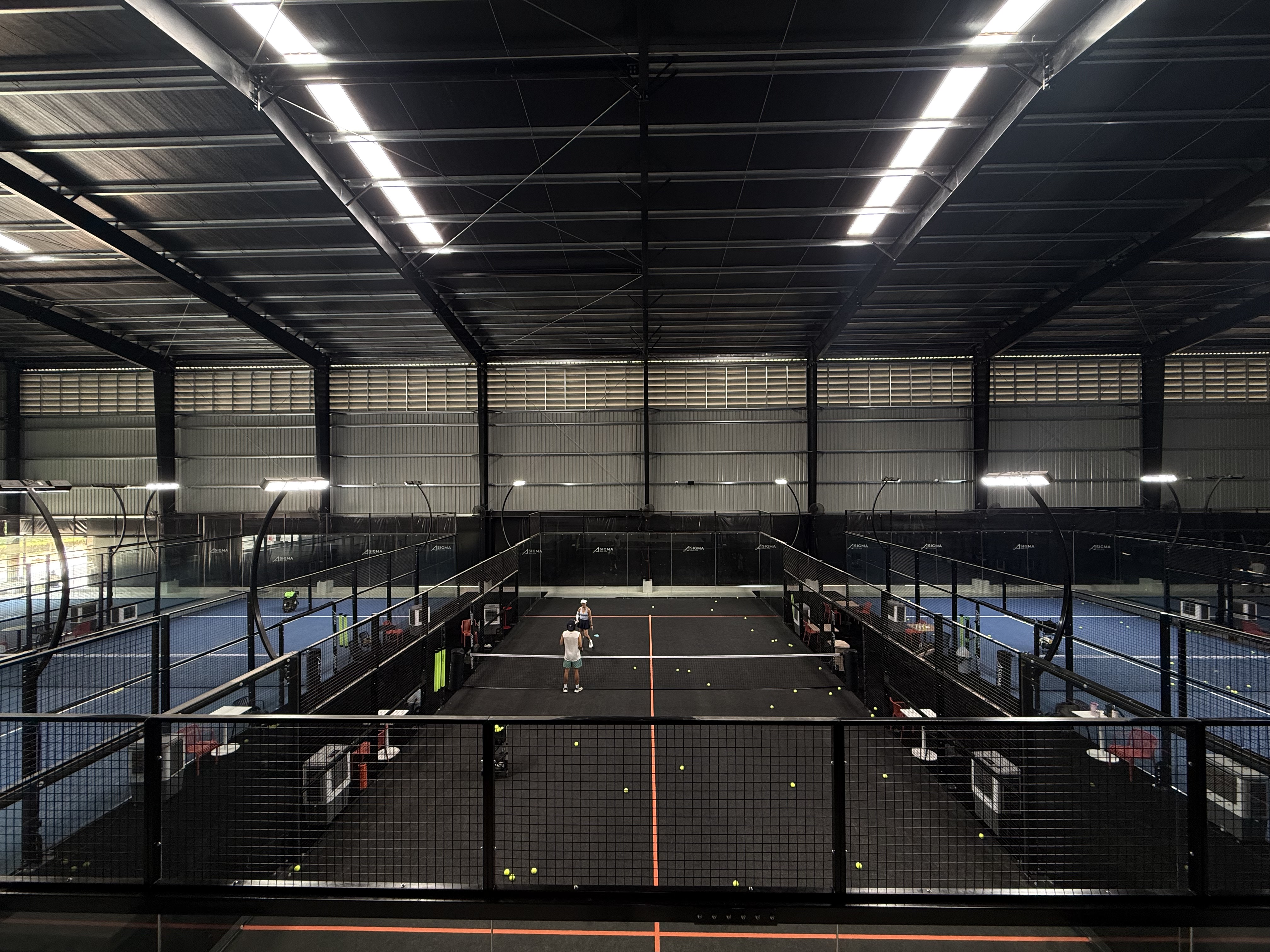 มุมกว้างคอร์ท padel ในร่ม กระจกรอบด้านโครงเหล็กดำ