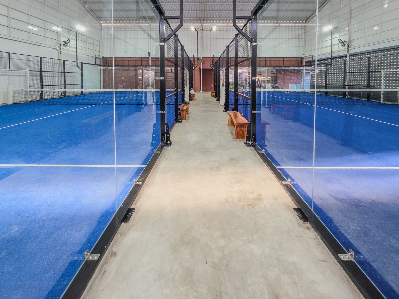 มุมกว้างคอร์ท padel ในร่ม กระจกรอบด้านโครงเหล็กดำ